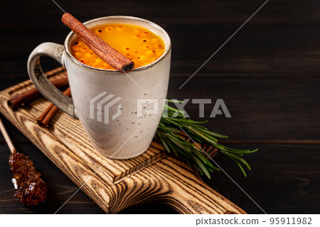 A cup of sea buckthorn hot drink on dark wooden background, copy space A cup of sea buckthorn hot drink on dark wooden background, copy space 95911982