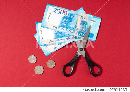 Russian rubles and scissors on a red background Russian rubles and scissors on a red background 95911985