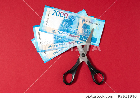 Russian rubles and scissors on a red background Russian rubles and scissors on a red background 95911986