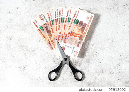 Russian rubles and scissors on a grey background Russian rubles and scissors on a grey background 95912002