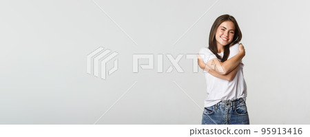 Attractive smiling tender woman hugging herself on white background. 95913416