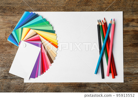 Color palette, pencils and blank paper sheet on wooden background, flat lay. Space for text 95913552