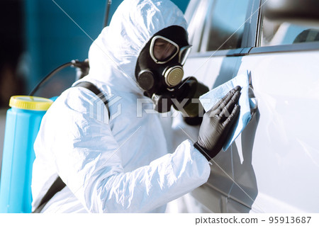 Hand of Man in protective suit washing and disinfection handles of a car.Pandemic in quarantine city 95913687
