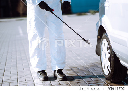 Man in protective suit washing and disinfection car wheels, to preventing the spread of the epidemic 95913702