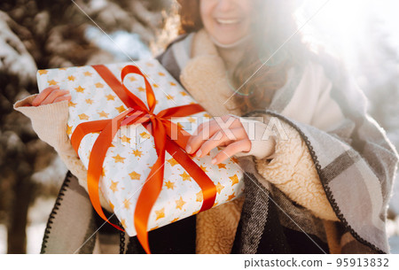 Pretty Woman holding a giftbox with red ribbon in the winter park. Happy winter time. New year's. Pretty Woman holding a giftbox with red ribbon in the winter park. Happy winter time. New year's. 95913832