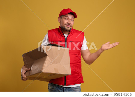 Emotional courier with damaged cardboard box on yellow background. Poor quality delivery service 95914106