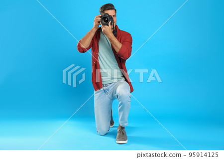 Professional photographer working on light blue background in studio 95914125