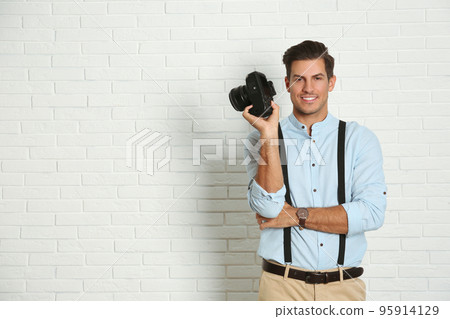 Professional photographer working near white brick wall in studio. Space for text Professional photographer working near white brick wall in studio. Space for text 95914129