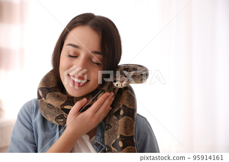 Young woman with her boa constrictor at home. Exotic pet 95914161