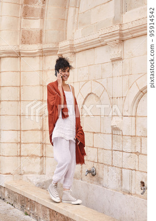 Stylish woman wearing trendy outfit walking at the street and talking via smartphone 95914542