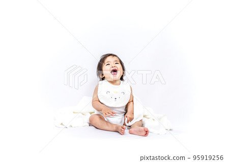 A baby girl sitting in front of a white background and laughing> 95919256
