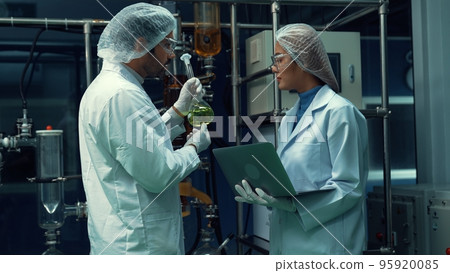 Two scientist in professional uniform working in laboratory Two scientist in professional uniform working in laboratory 95920085