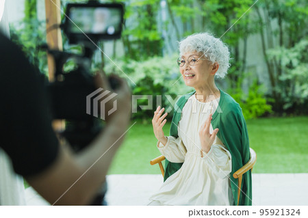 Photographer taking video of senior woman Photographer taking video of senior woman 95921324