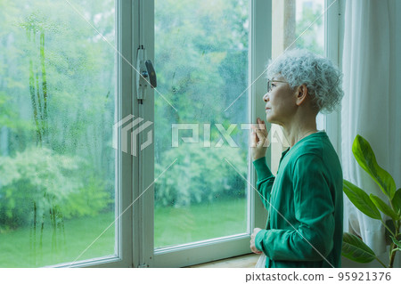 Senior woman by the window in the rain 95921376