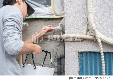 Male worker painting the exterior walls of a house 95921676