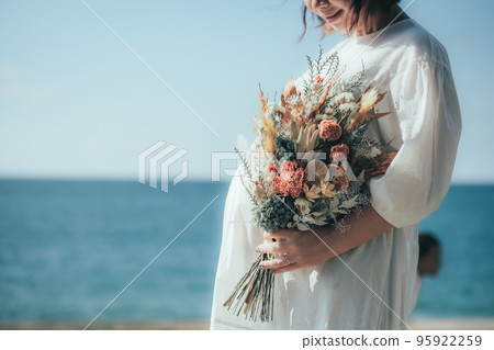 Pregnant woman with a bouquet at the beach Pregnant woman with a bouquet at the beach 95922259