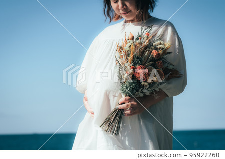 Pregnant woman with a bouquet at the beach 95922260