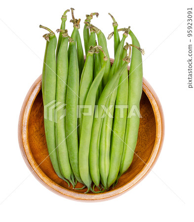 Fresh green beans in a wooden bowl. Young, unripe fruits of a cultivar of the common bean or also French bean, Phaseolus vulgaris. Close-up, isolated from above, on white background, macro food photo. Fresh green beans in a wooden bowl. Young, unripe fruits of a cultivar of the common bean or also French bean, Phaseolus vulgaris. Close-up, isolated from above, on white background, macro food photo. 95923091