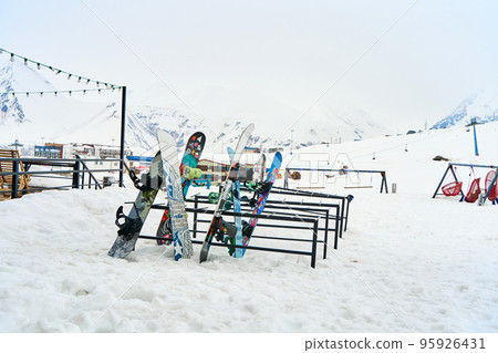 A snowboard stand outside in front of a restaurant in a ski resort. Parking for snowboards and skis 95926431