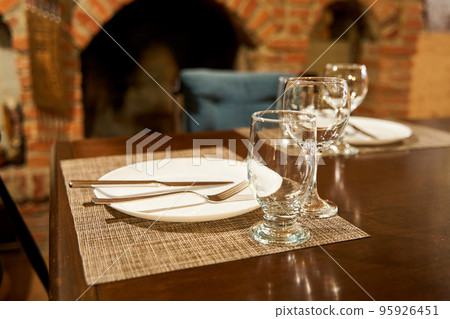 A table with clean dishes in a cozy cafe with a fireplace A table with clean dishes in a cozy cafe with a fireplace 95926451
