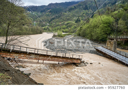 A bridge over a mountain river destroyed by water A bridge over a mountain river destroyed by water 95927760