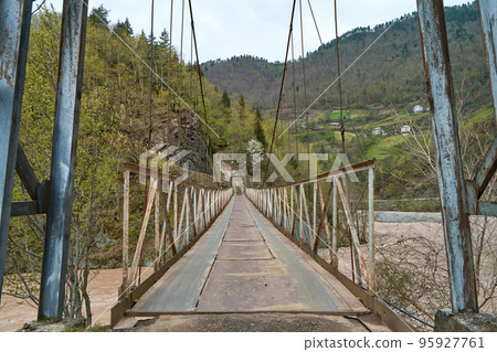 Wobbly old bridge over a mountain river for cars. 95927761