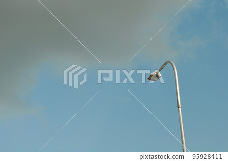 A TURNED OFF STREET LIGHT AND BLACK CLOUD IN BLUE SKY BACKGROUND  95928411