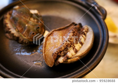 Dinner Close-up of live abalone dancing on the iron plate before cooking (Chiba) 95928688