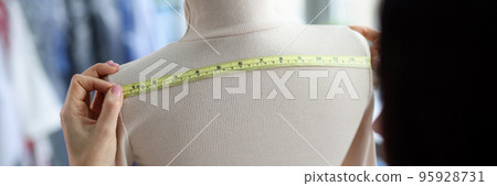 Female fashion designer takes measurements with centimeter 95928731