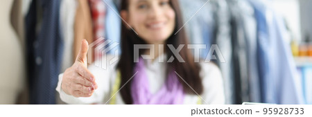 Woman seamstress giving hand for handshaking, bright sewing accessories on table Woman seamstress giving hand for handshaking, bright sewing accessories on table 95928733