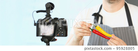 Male chef in apron showing chillies pepper on camera Male chef in apron showing chillies pepper on camera 95928805