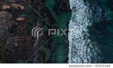 Waves break on the rocky shore of the Celtic Sea, top view. White foam on the waves. The coastline of the Atlantic. Turquoise water. Breathtaking seaside landscape. Waves break on the rocky shore of the Celtic Sea, top view. White foam on the waves. The coastline of the Atlantic. Turquoise water. Breathtaking seaside landscape. 95931436