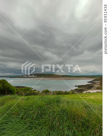 Thick green grass on a hill near the sea bay. Cloudy sky over Clonakilty Bay, seascape. Aerial photo. Thick green grass on a hill near the sea bay. Cloudy sky over Clonakilty Bay, seascape. Aerial photo. 95931438