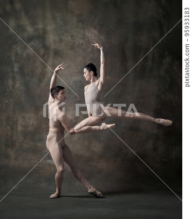 Young man and woman, ballet dancers performing isolated over dark green vintage background. Attraction of beauty 95933183