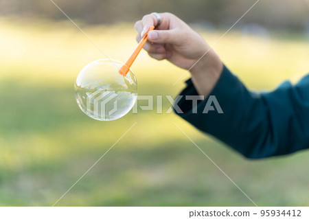 公園裡拿著肥皂泡的男手 95934412