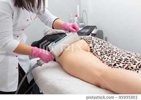 The masseur does a massage using anti-cellulite massage machine with compression and vibration technology in beautician office. The masseur does a massage using anti-cellulite massage machine with compression and vibration technology in beautician office. 95935801