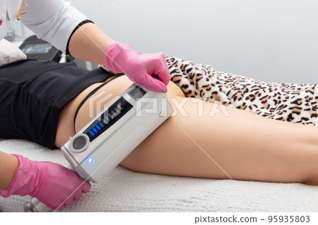 The masseur does a massage using anti-cellulite massage machine with compression and vibration technology in beautician office. The masseur does a massage using anti-cellulite massage machine with compression and vibration technology in beautician office. 95935803