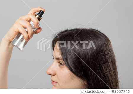 The girl puts on her hair a tonic of hydrolyte from a bottle. Hair care at home. 95937745