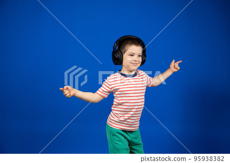 Happy smart 5 year old boy in big black headphones points fingers to the sides in place for text copy space Happy smart 5 year old boy in big black headphones points fingers to the sides in place for text copy space 95938382