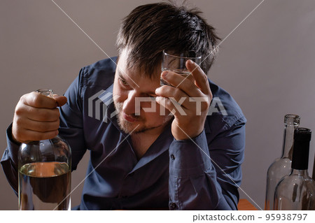 A man in alcoholic intoxication holds a glass of alcohol. Alcoholism, addiction, delirium 95938797