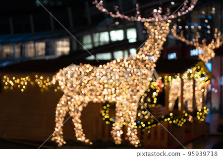 Blurred lights of christmas installation - defocused lights of deer on night city background. Christmas deer installation in Milan 95939718