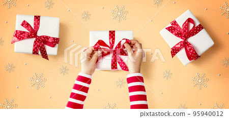 Person making Christmas gift boxes 95940012