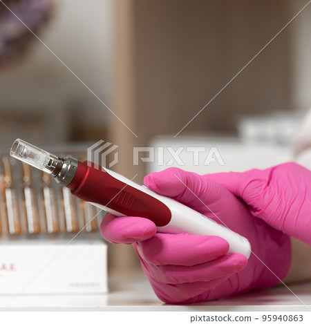 The beautician holds in his hands a dermapen, a tool for mesotherapy and cell regeneration. The beautician holds in his hands a dermapen, a tool for mesotherapy and cell regeneration. 95940863