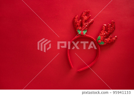 Christmas deer antlers in hipster style on red surface. Colorful reindeer antlers headband. Holiday costume detail. Copy space 95941133