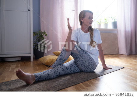 Mature caucasian woman doing twisted yoga pose training at home 95941832