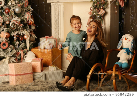 cute little blond baby girl and mom on Christmas tree and fire place background cute little blond baby girl and mom on Christmas tree and fire place background 95942289