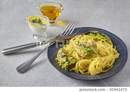 Chkemeruli on a dark plate with cutlery and gravy boats with oill and cream Chkemeruli on a dark plate with cutlery and gravy boats with oill and cream 95942473