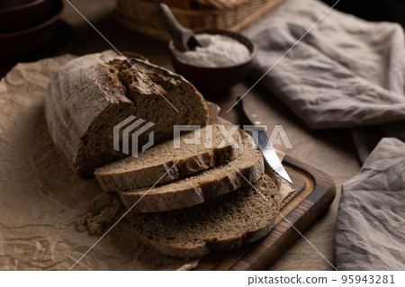 Sliced homemade bread with parchment paper at wood table. Bread on wooden tabletop 95943281