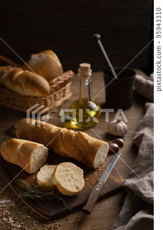 Sliced french bread with cutting board at wood table. Homemade bread on wooden tabletop 95943310