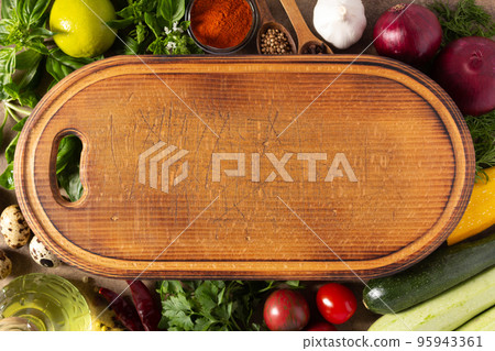 Variety of fresh vegetables and wood cutting board at table background. Cooking concept and salad 95943361